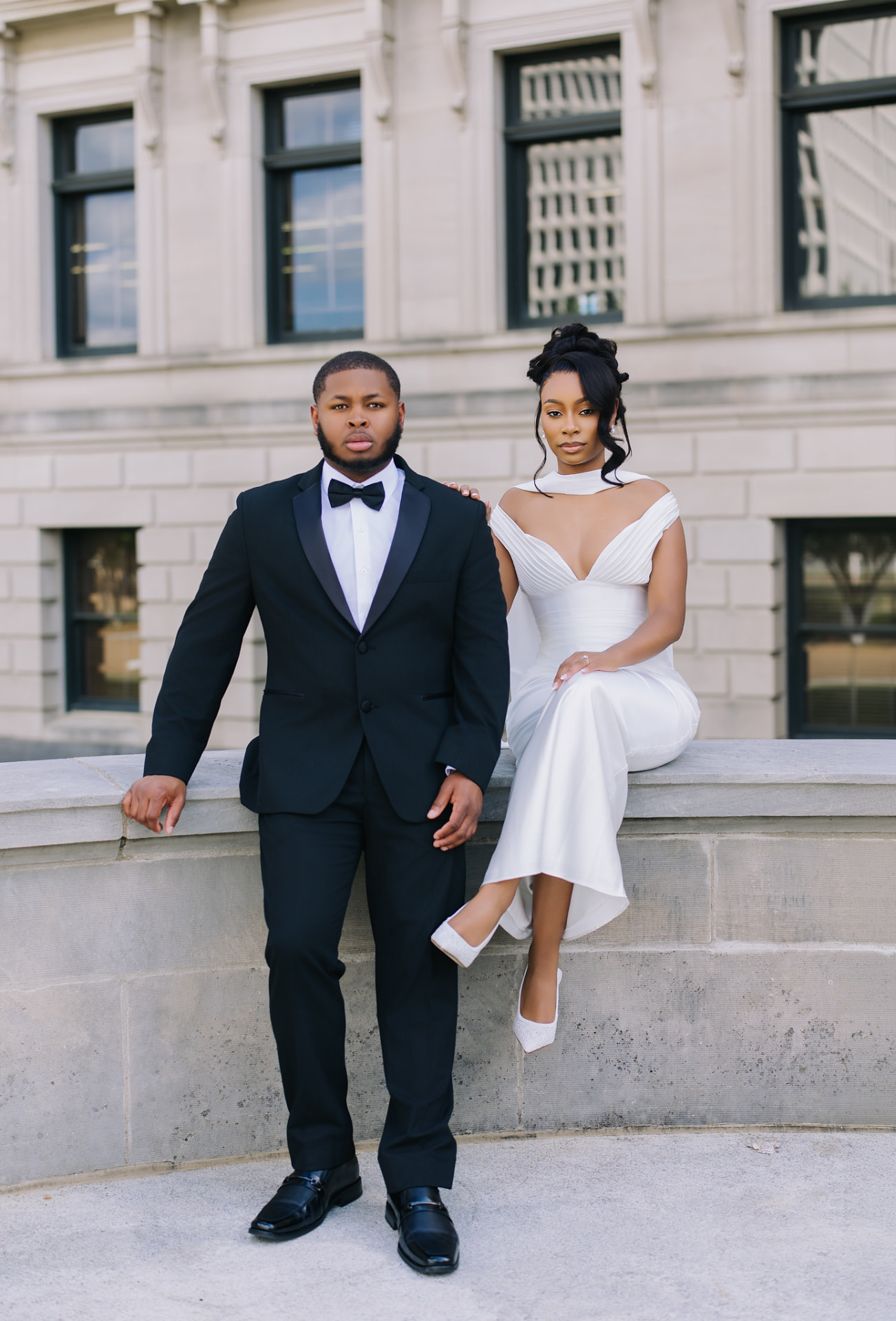 Engaged couple in formal attire outside a historic building
