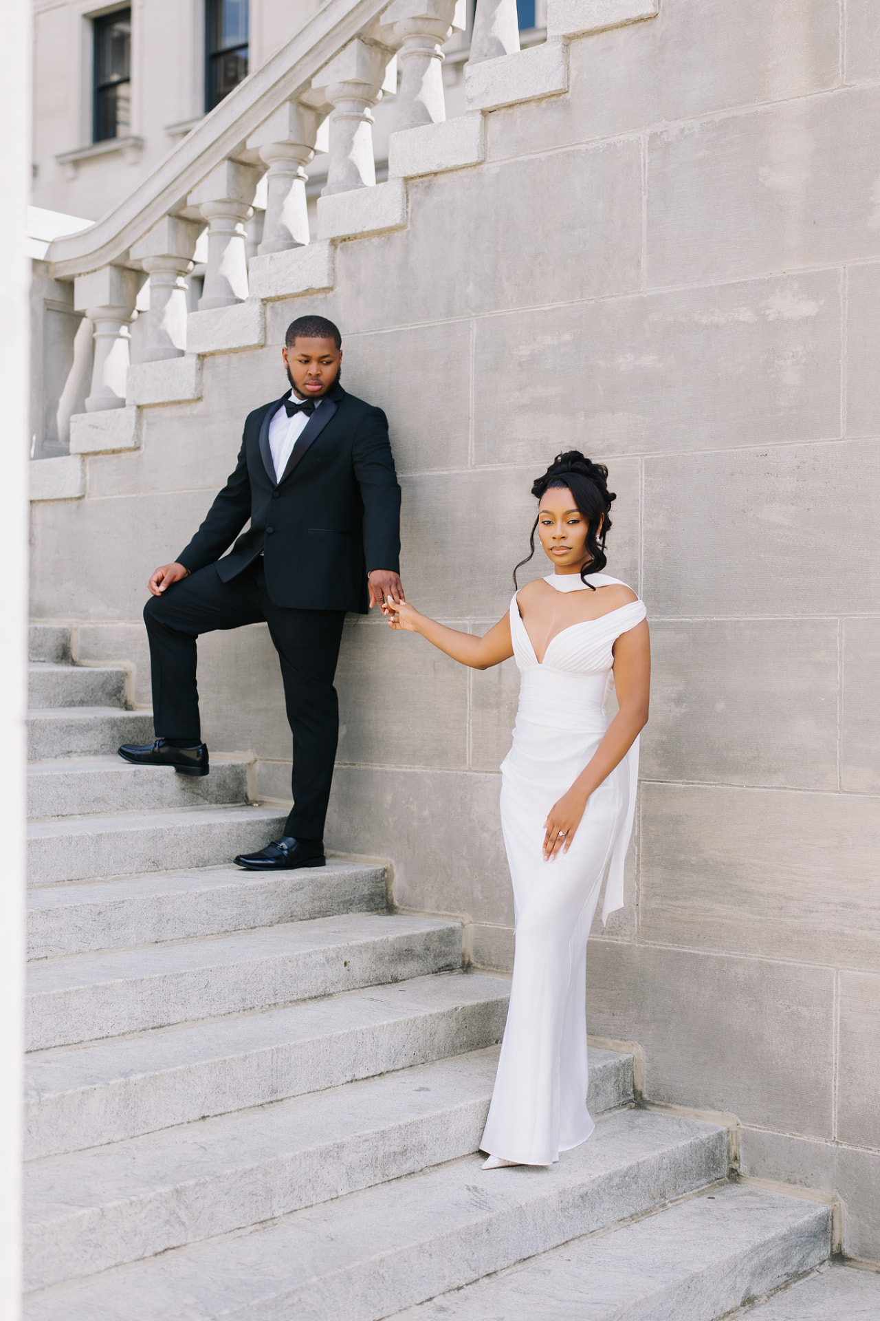 Engaged couple holding hands on grand stone steps