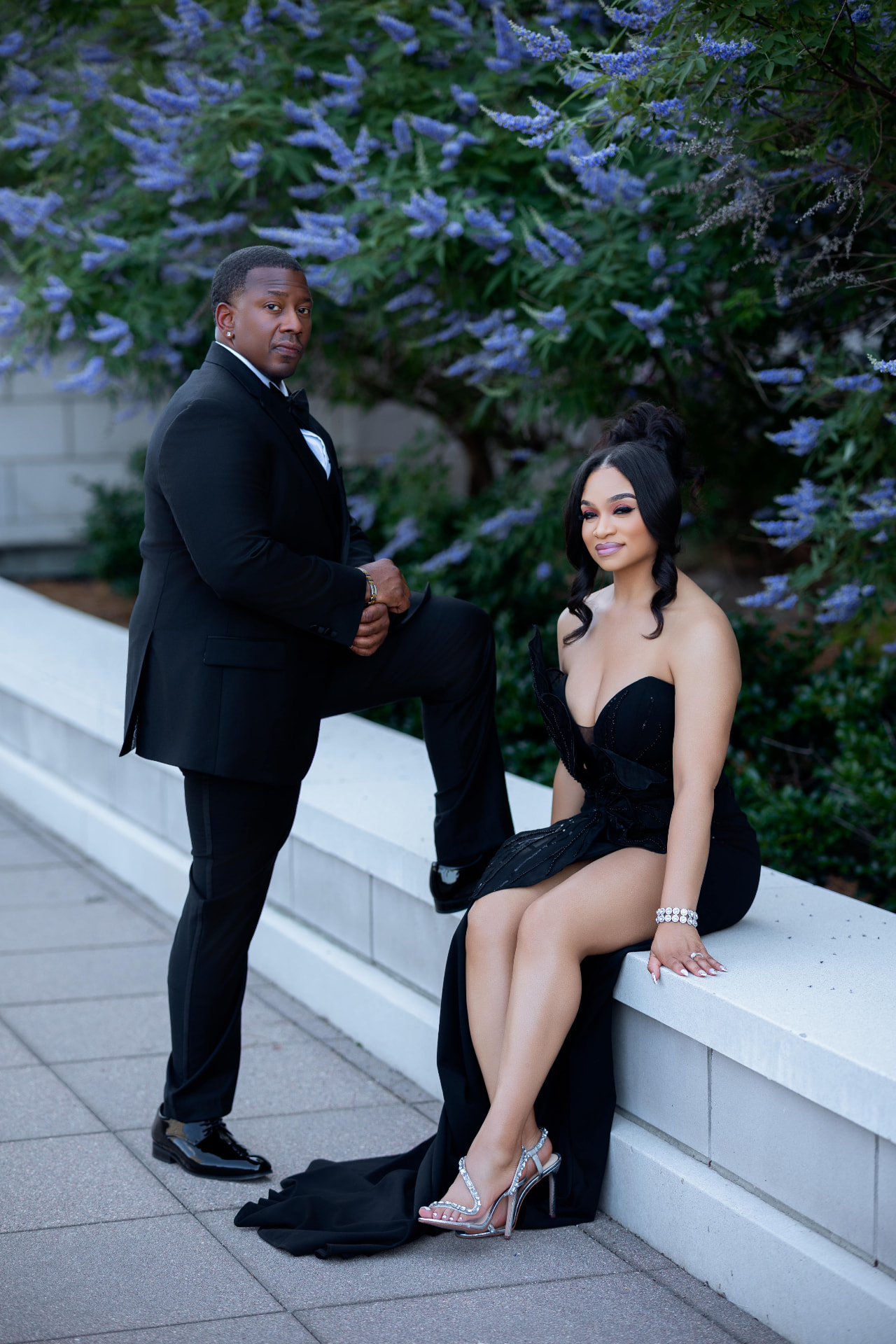 Engaged couple posing together beneath flowering trees