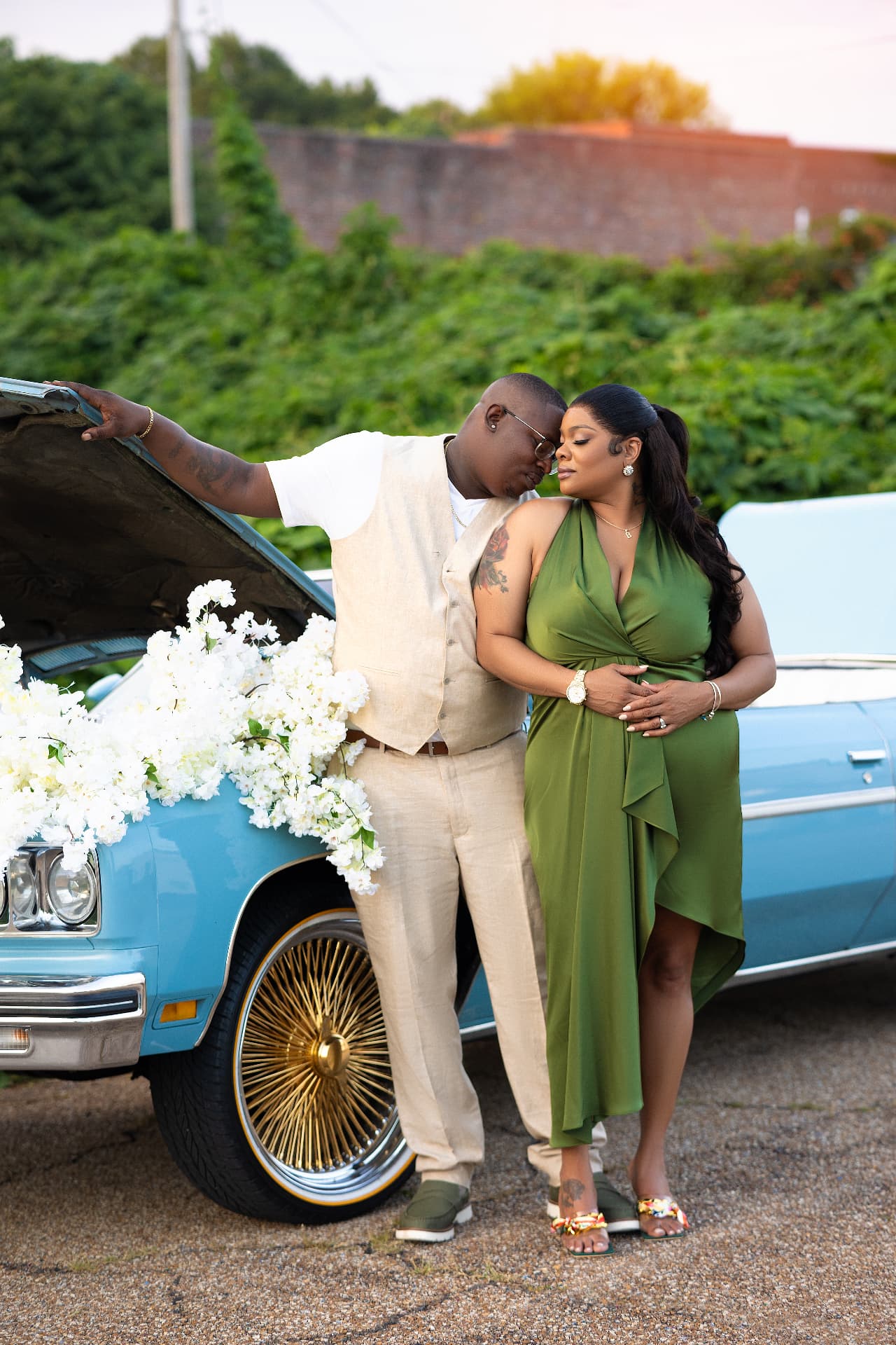 Engaged couple resting head to head by a flower-adorned vintage car